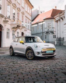 A vibrant yellow compact car parked on a cobblestone street.