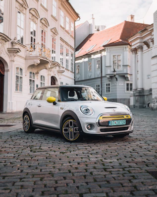 A vibrant yellow compact car parked on a cobblestone street.