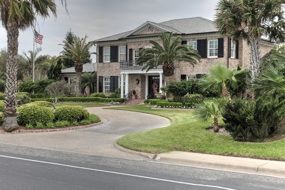 green grass and green plants in front of brown and white concrete house