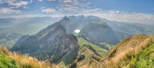 green grass field and mountains under blue sky during daytime in Hoher Kasten Switzerland