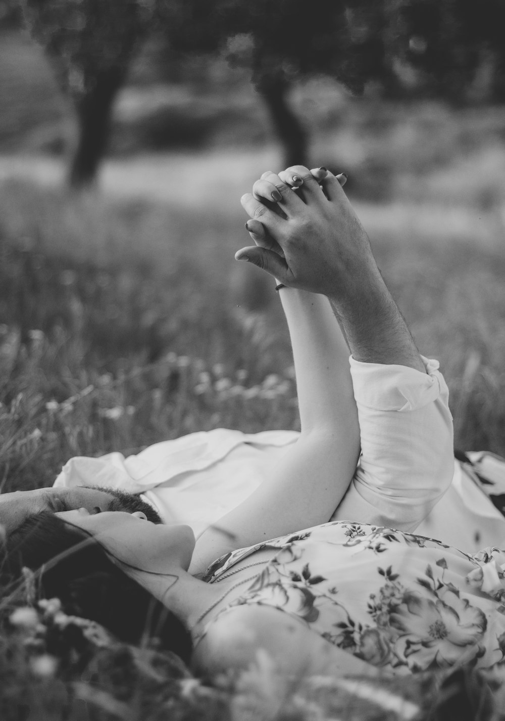 grayscale photo of woman in white dress lying on grass field