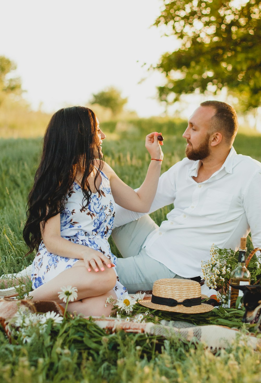 man and woman sitting on grass field during daytime