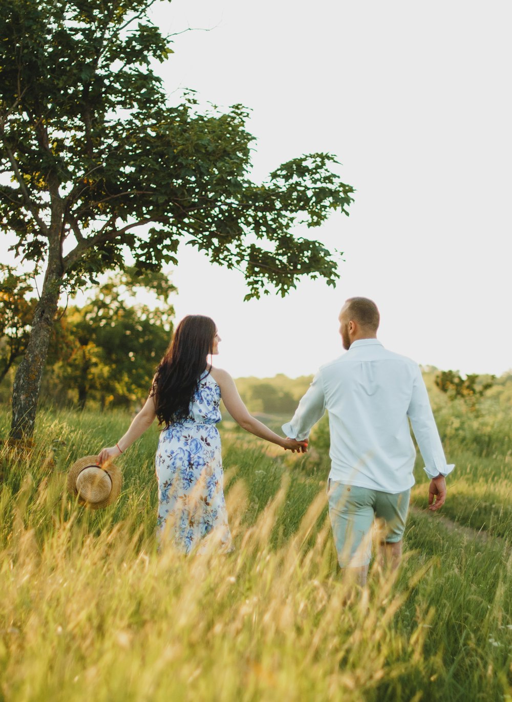 man and woman holding hands while walking on green grass field during daytime