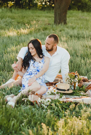 A couple enjoying a peaceful picnic in a sunlit park with soft cream and green shades.