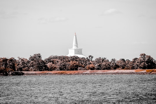 white lighthouse on brown rock formation near body of water during daytime in Anuradhapura Sri Lanka
