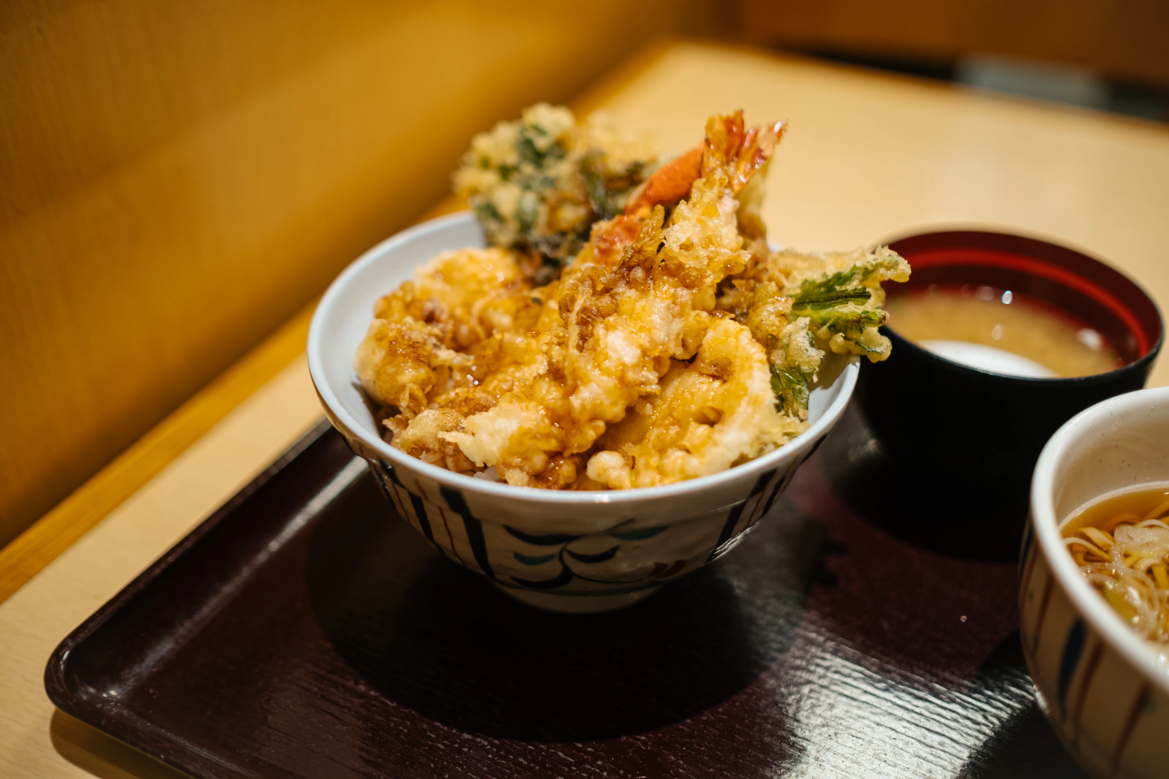 Tempura prawns over a rice bowl at a counter