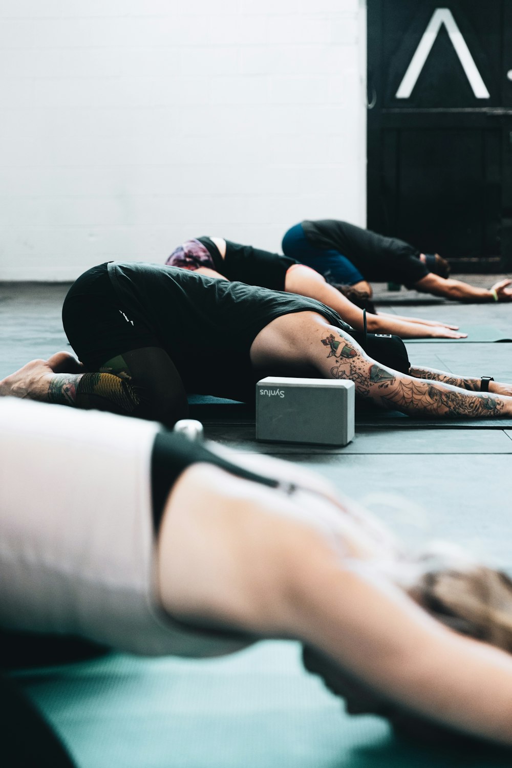 woman in black tank top and black leggings lying on floor