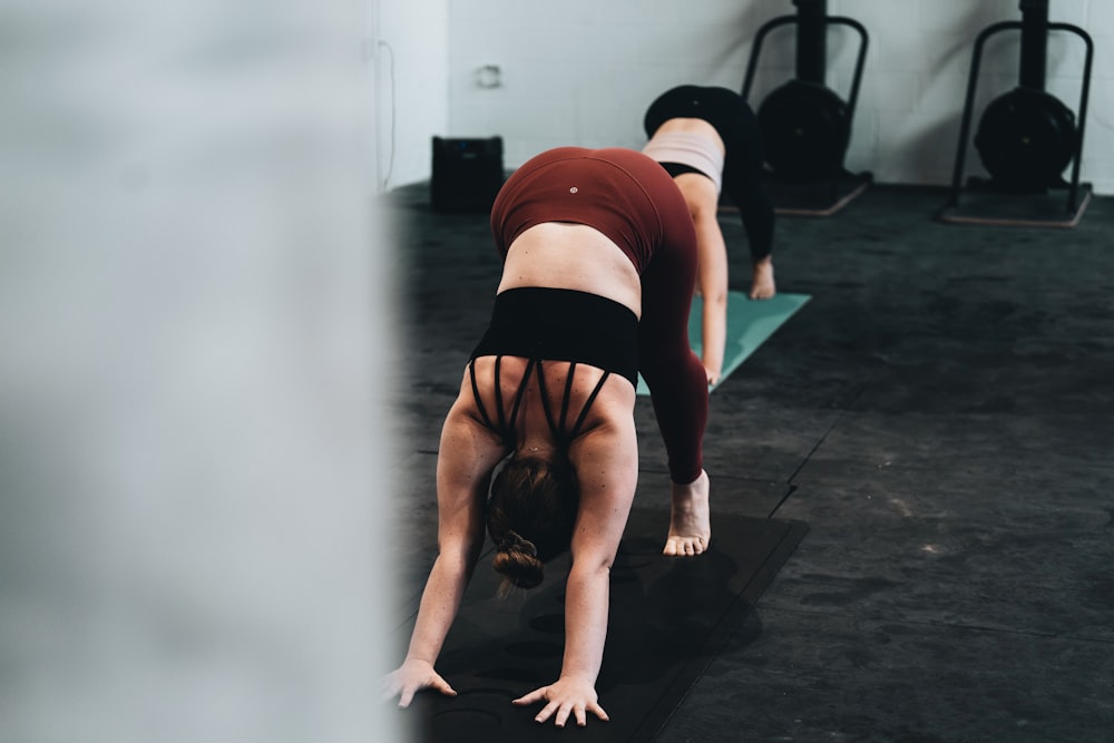 woman in red tank top and black shorts doing yoga