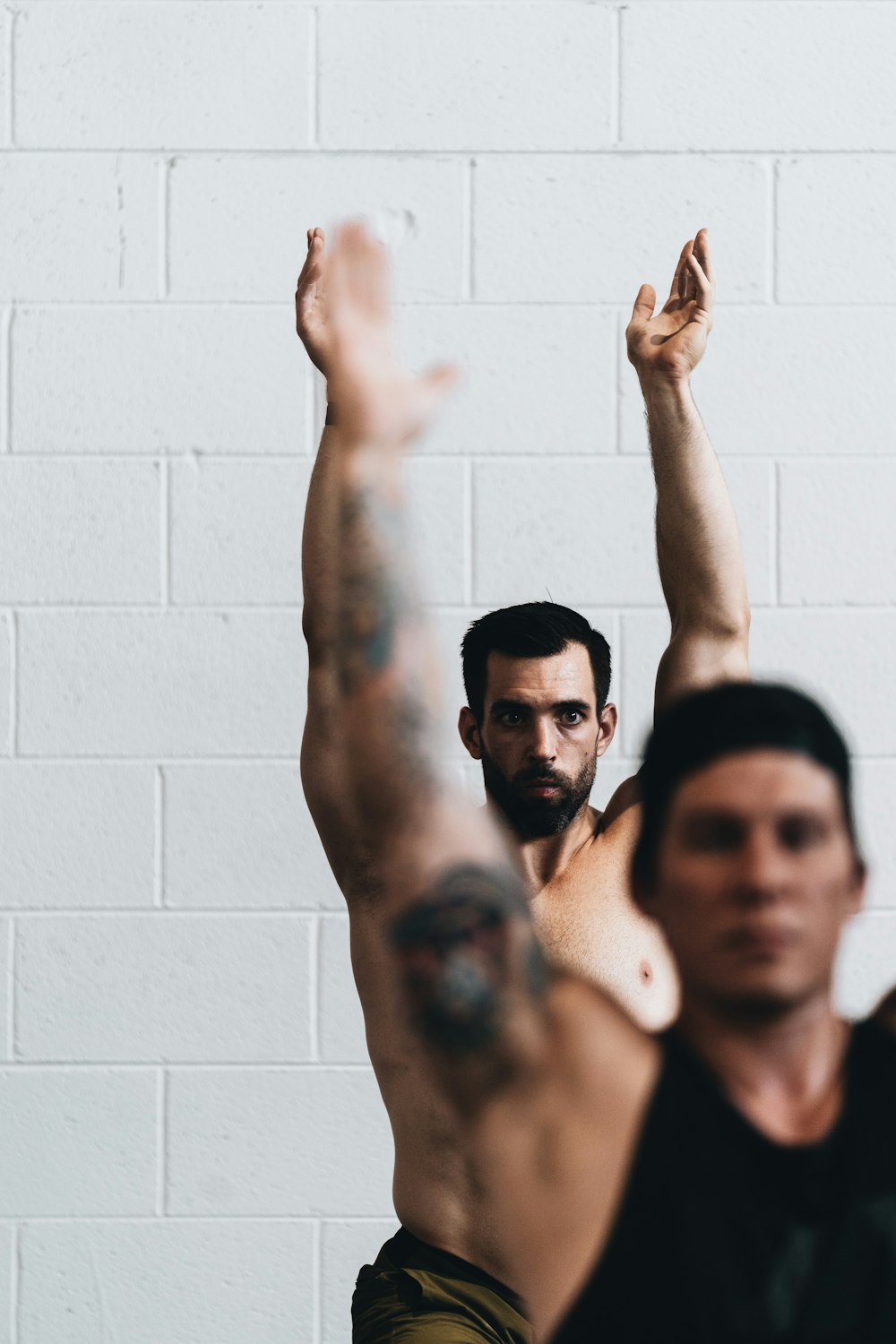 man in black tank top raising his hands