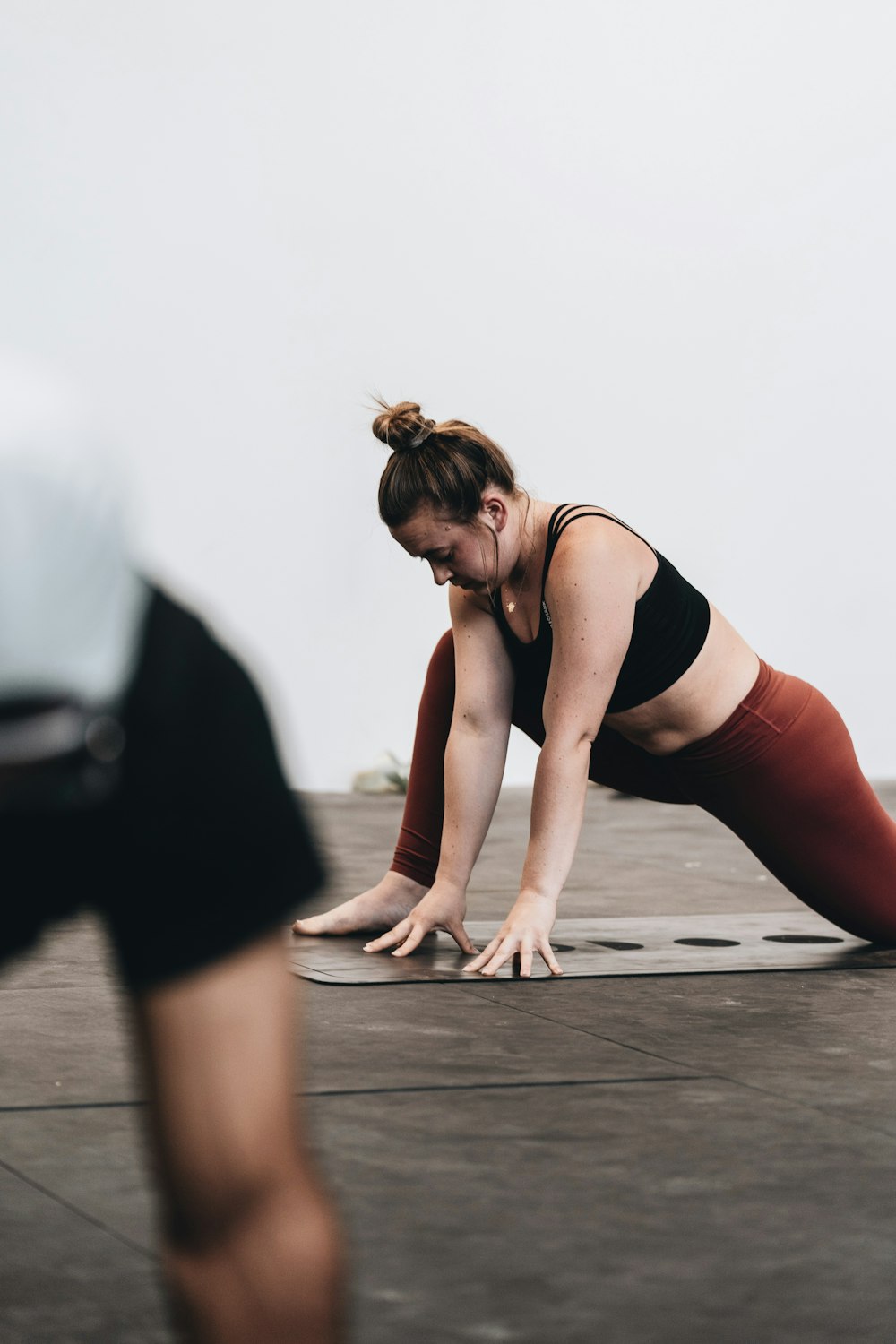 mulher na regata preta e calças brancas que fazem yoga