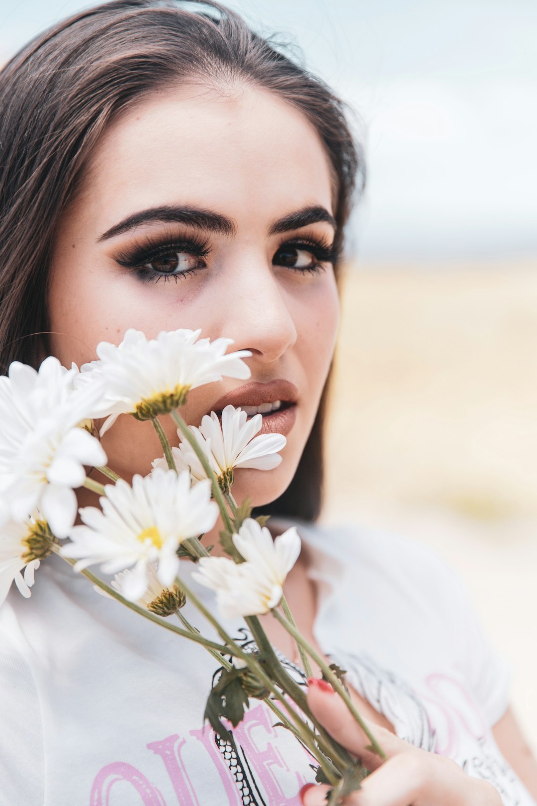 woman in white long sleeve shirt holding white flowers