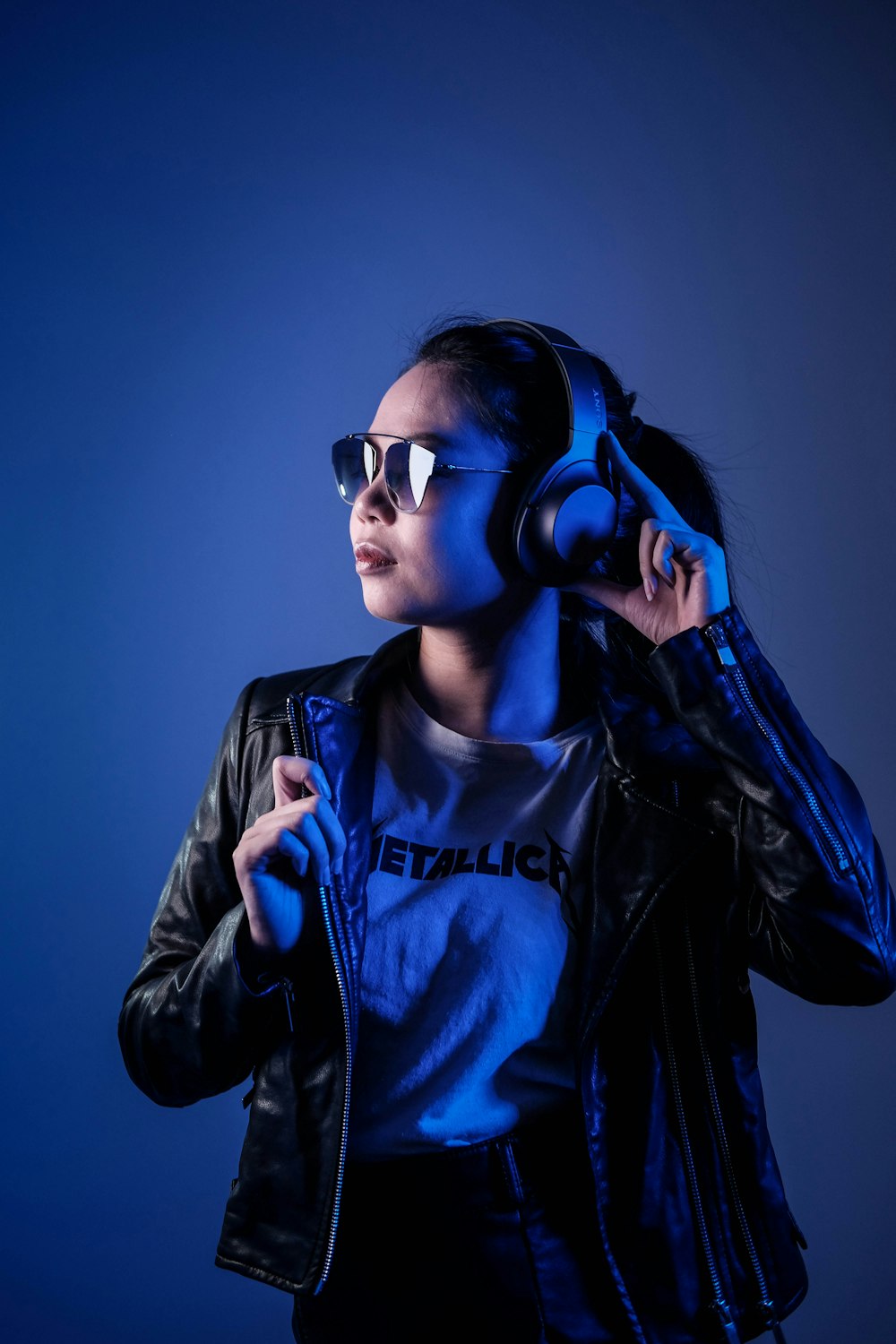 woman in black leather jacket wearing blue sunglasses