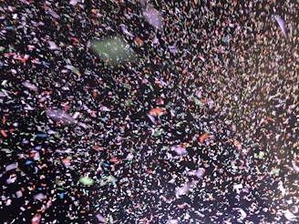 Close-up of a rotary die cutting machine shaping colorful confetti pieces.