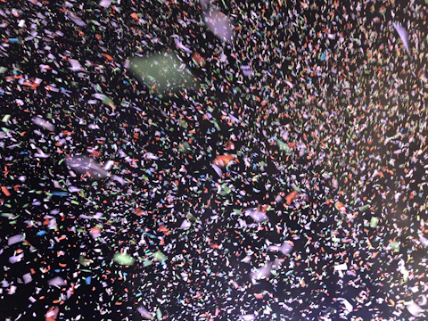 Close-up of a rotary die cutting machine shaping colorful confetti pieces.