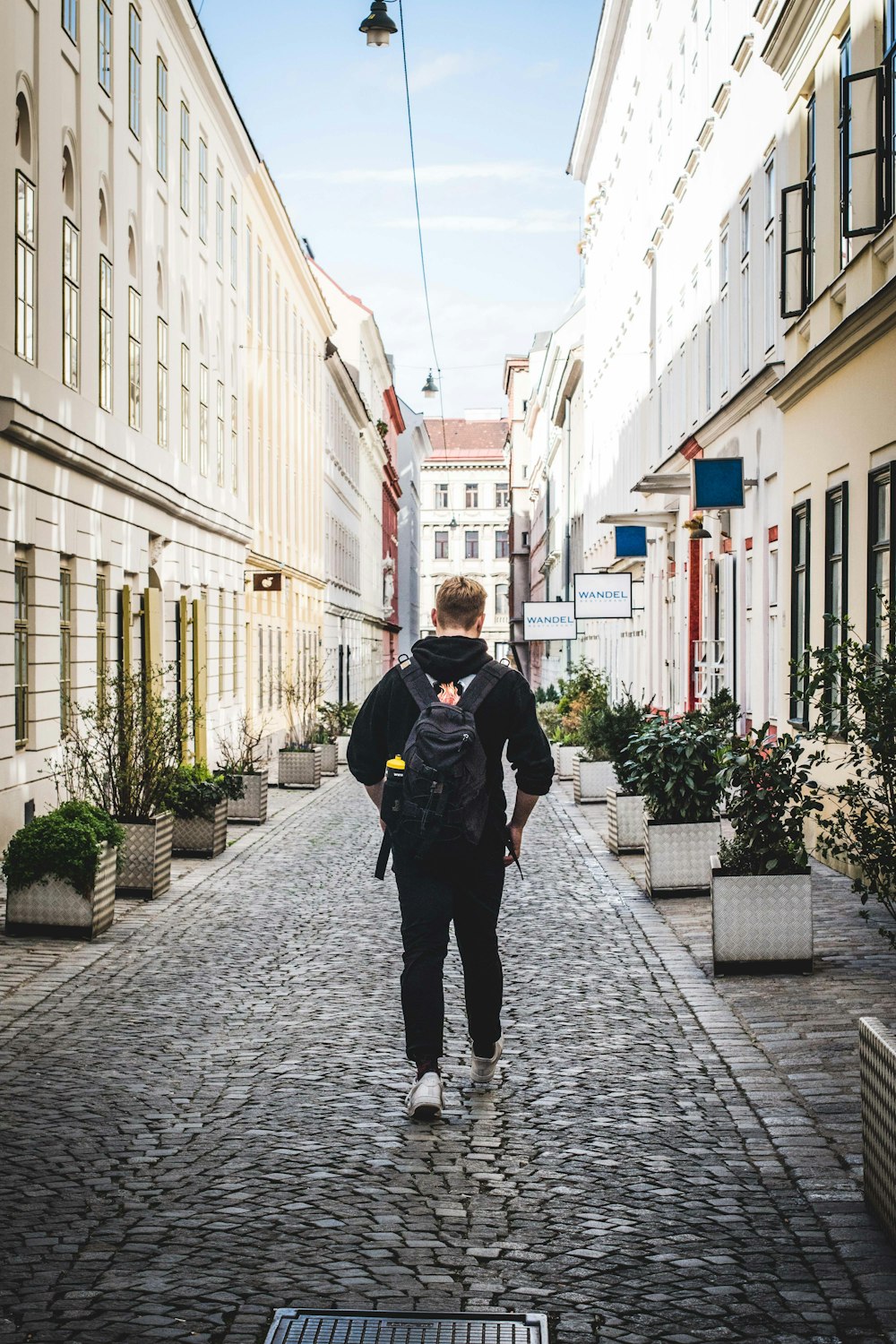 man in black jacket walking on sidewalk during daytime