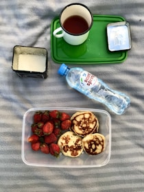 A cozy setup with a journal, a cup of tea, and supplement bottles on a rustic wooden surface.