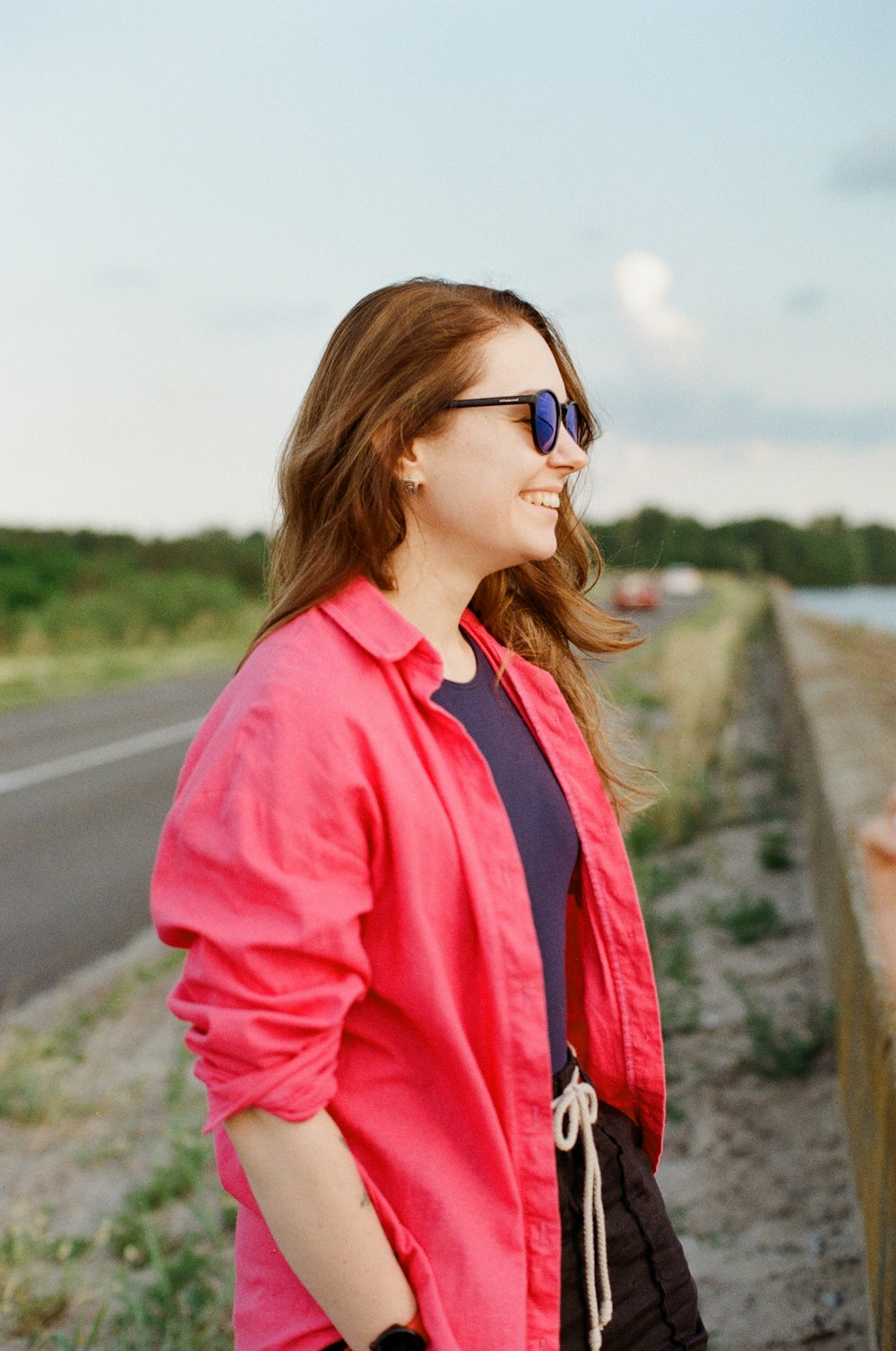 woman in red jacket standing on road during daytime