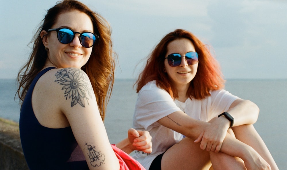 woman in white long sleeve shirt wearing blue sunglasses sitting on red textile