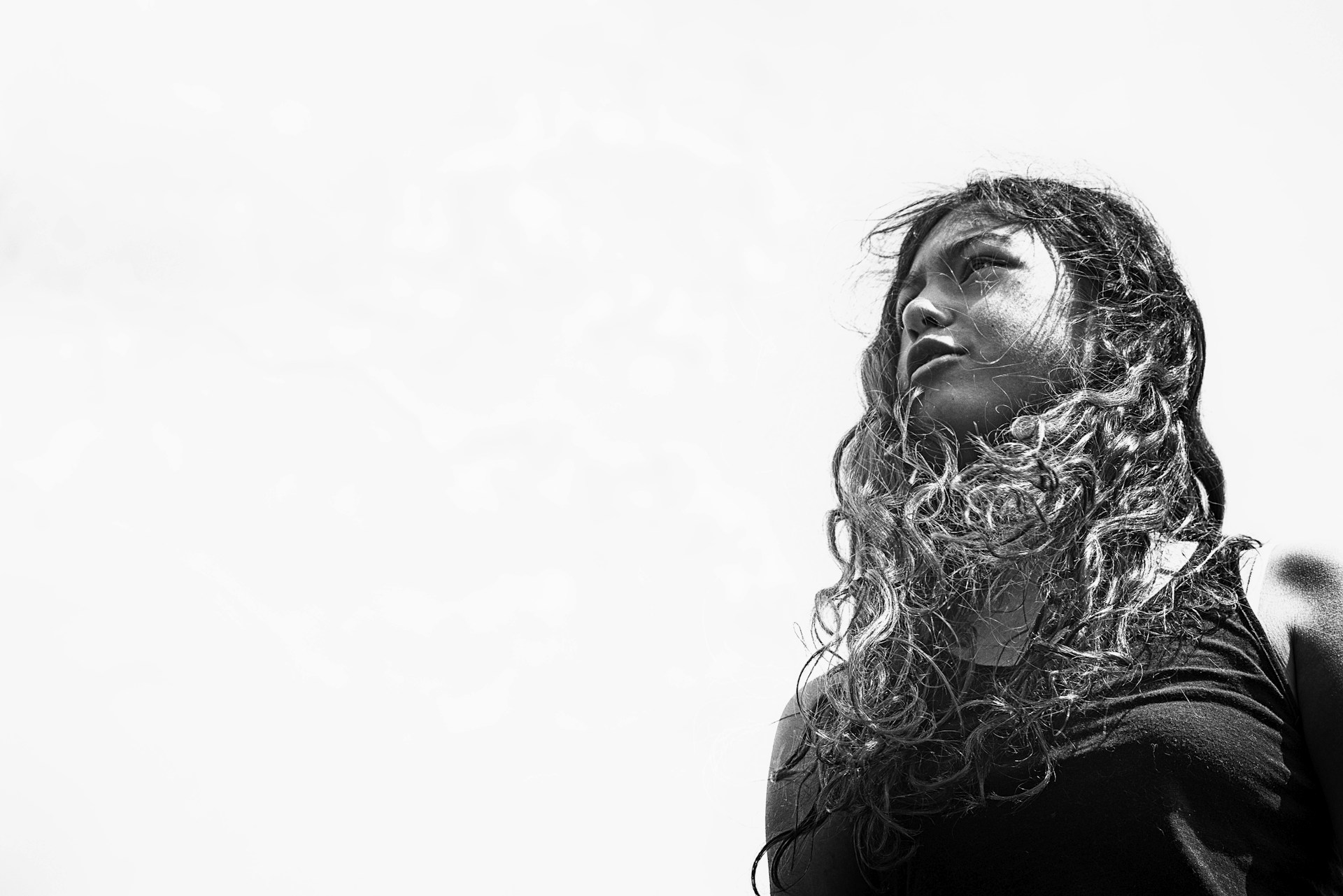 A vibrant photo of a young Black woman with long, flowing natural curls styled beautifully, showcasing the rich texture of underground luxe human hair.