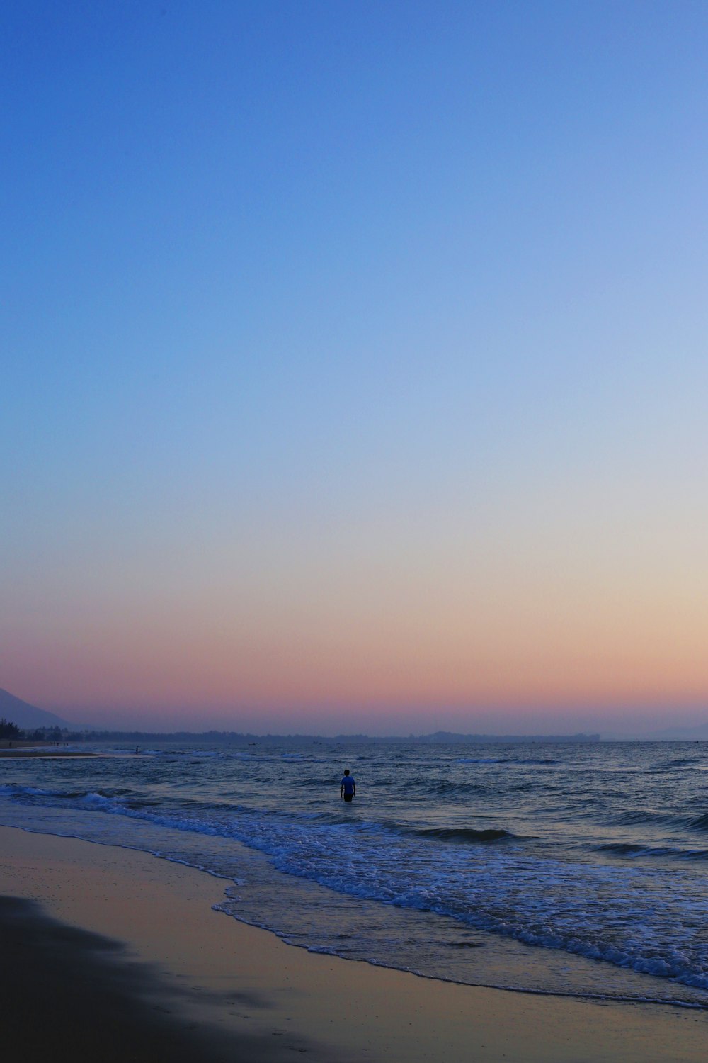 Silhouette der Person, die während des Sonnenuntergangs am Strand steht