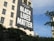 A large banner reading 'AFL-CIO Supports Black Lives Matter' hangs prominently on the side of a beige building. In the foreground, the tops of green trees are visible, and the sky is clear with a bright blue hue. Partially obscured by the trees, a domed building with a gold-colored top is visible.