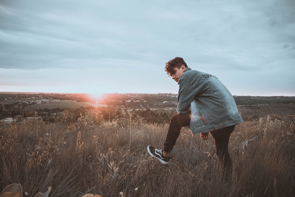 man in green shirt and black shorts standing on grass field during sunset