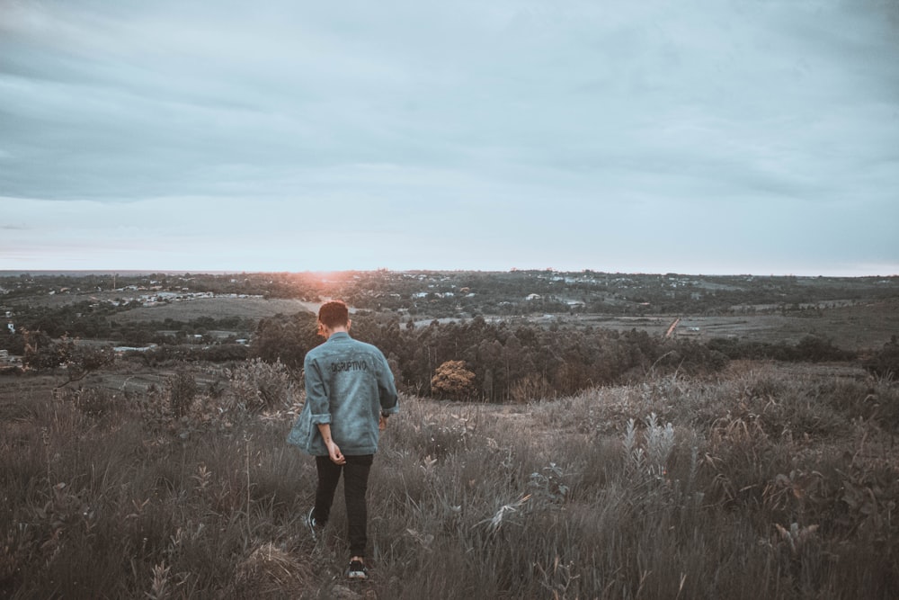 man in gray hoodie standing on brown grass field during daytime