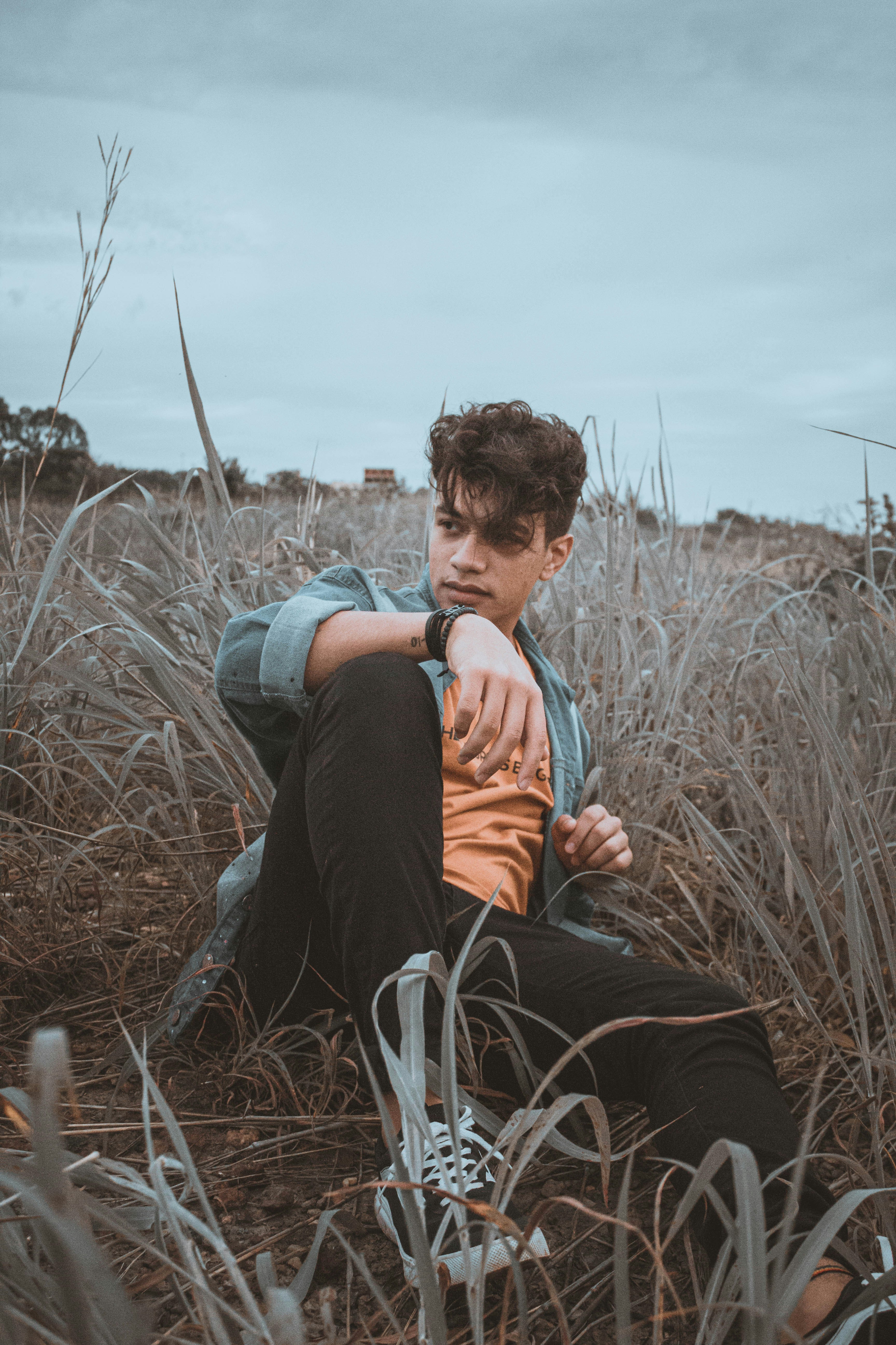 hombre con camisa naranja y pantalones negros sentado en una silla negra