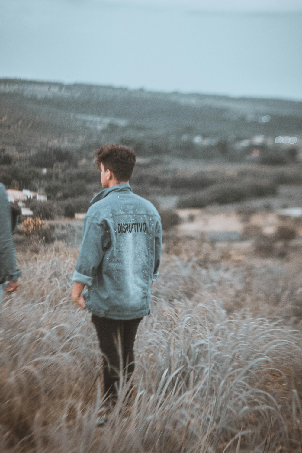 man in gray hoodie standing on brown grass field during daytime