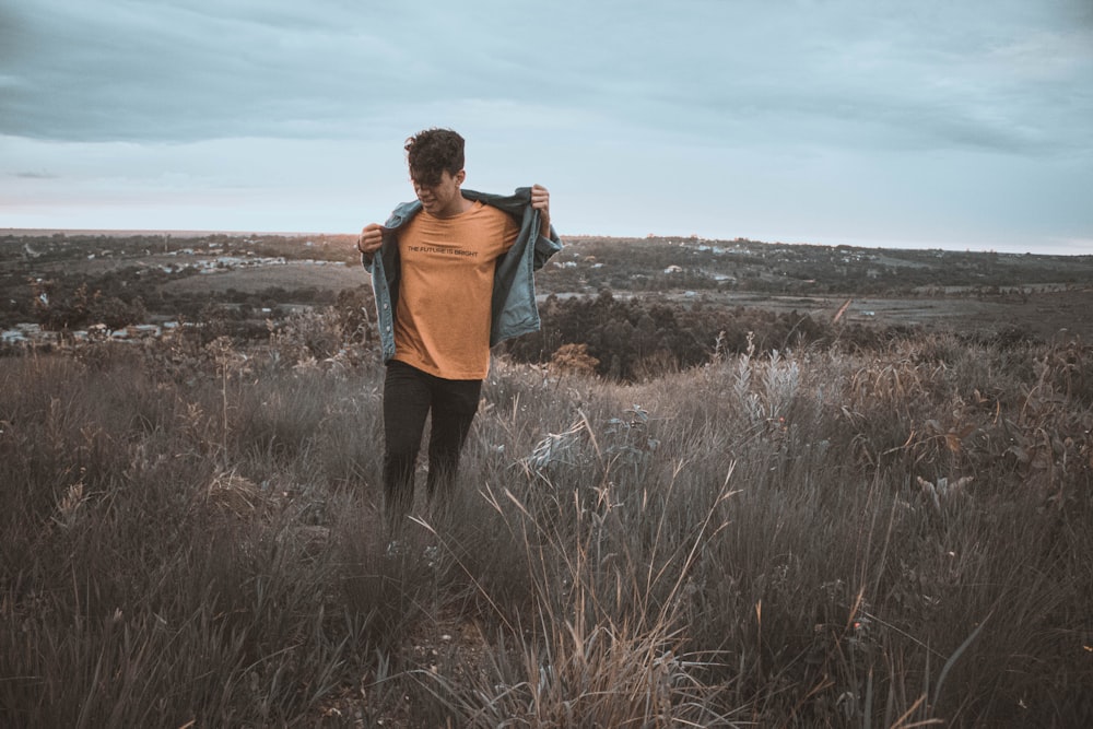 woman in orange long sleeve shirt standing on brown grass field during daytime