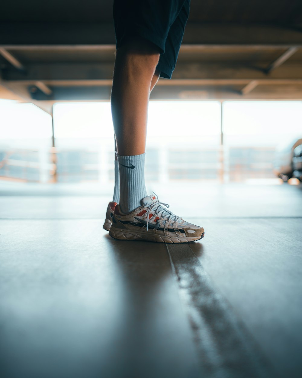 person in blue denim shorts and gray and black nike athletic shoes