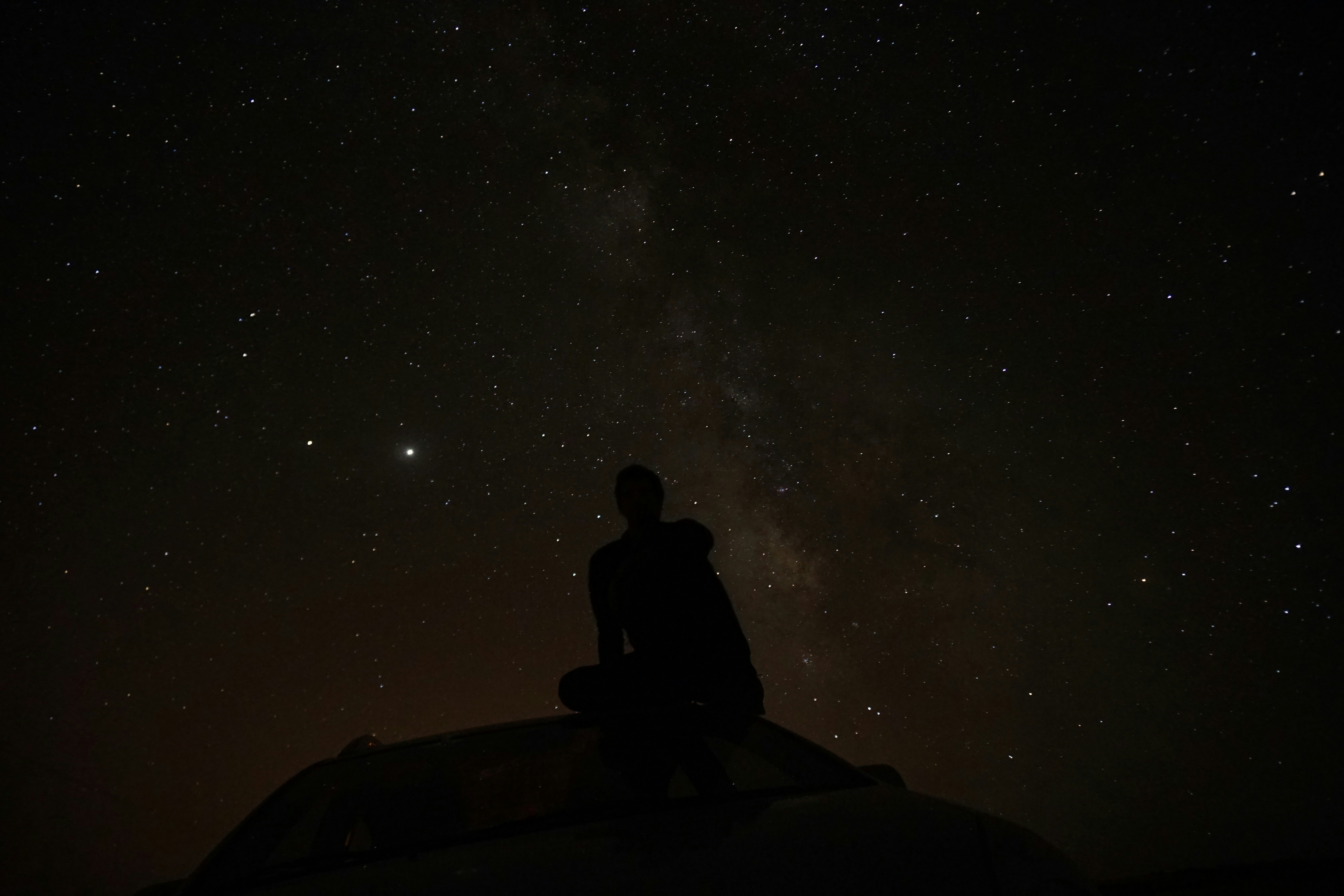 A man with a car under the stars and the Milky Way