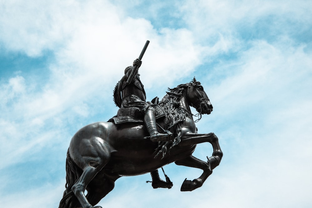 man riding horse statue under blue sky during daytime