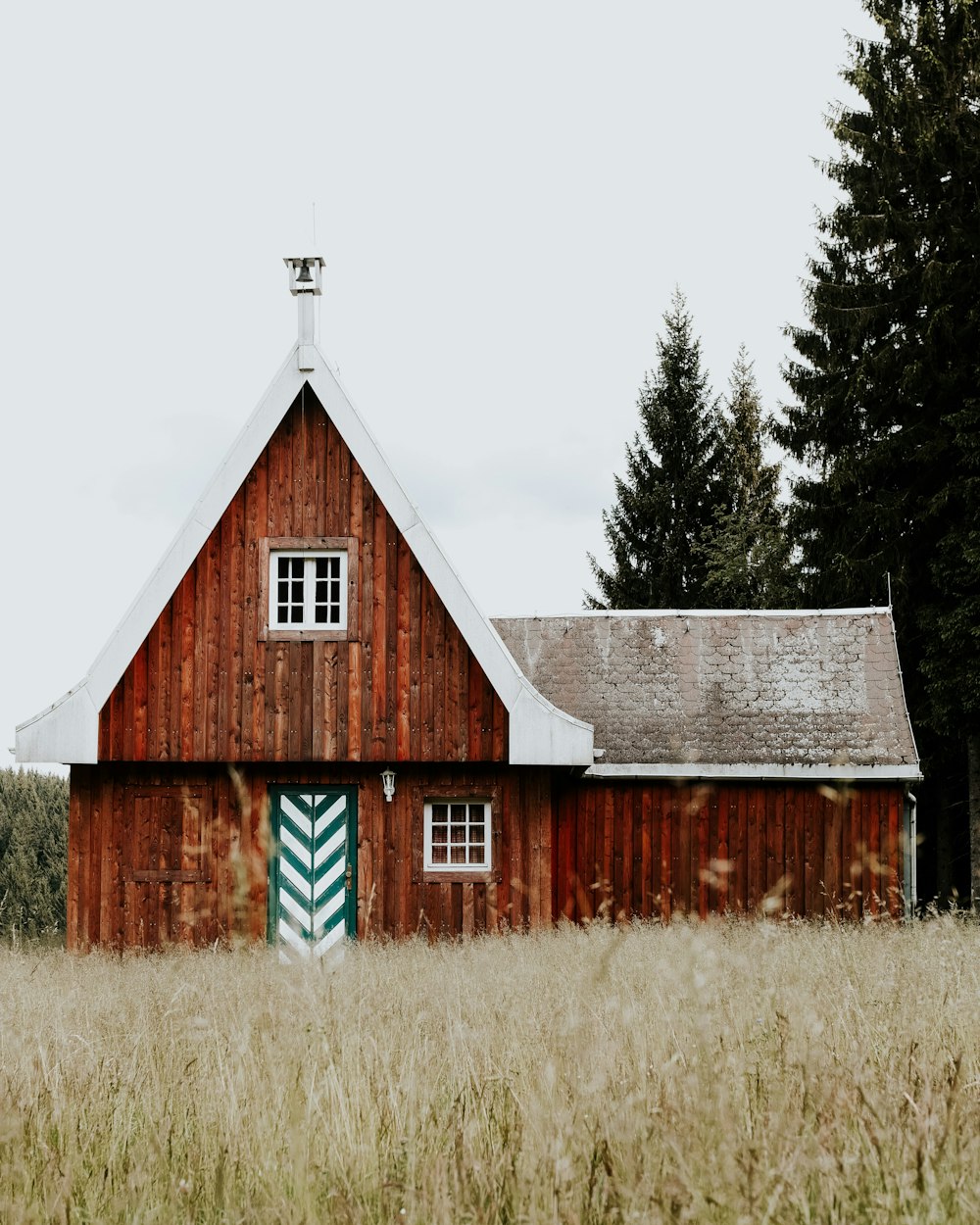 brown and white wooden house near green trees under white sky during daytime