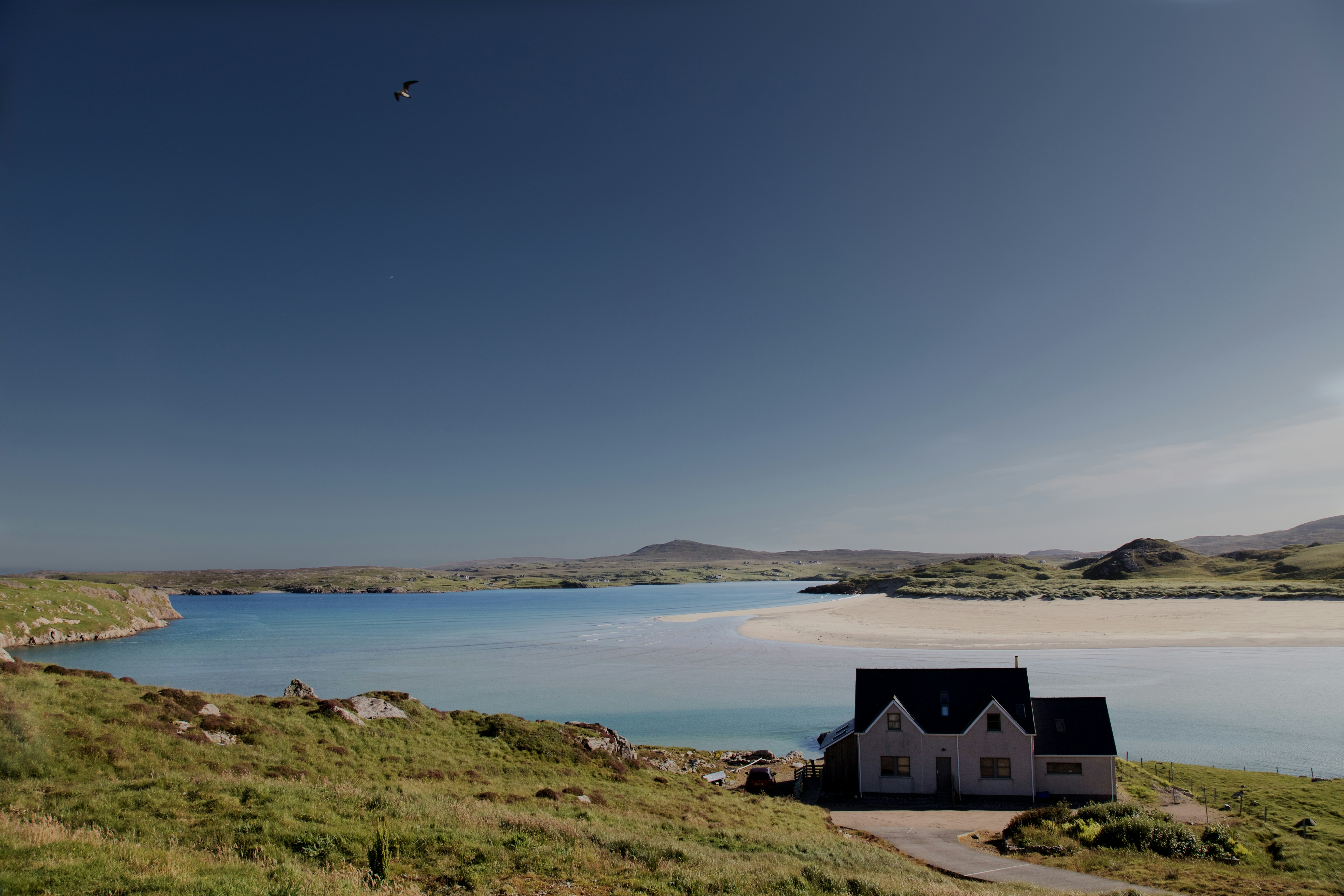 Lone house in a rugged landscape beside the sea.