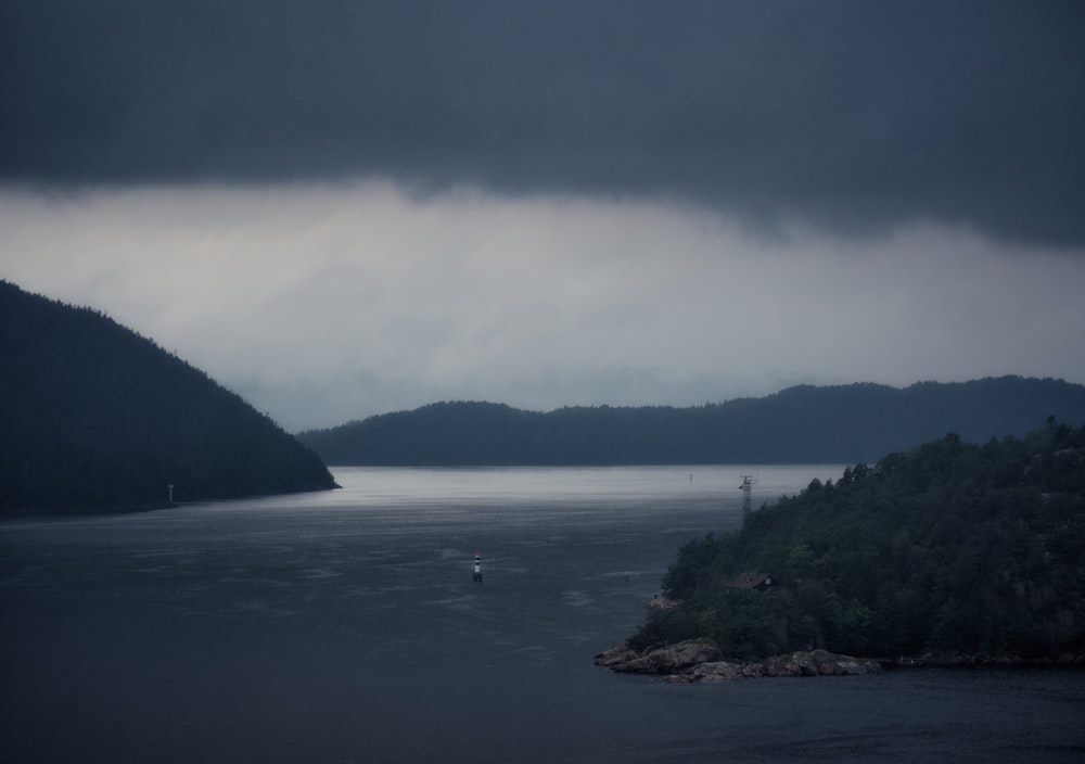 green trees near body of water under white clouds