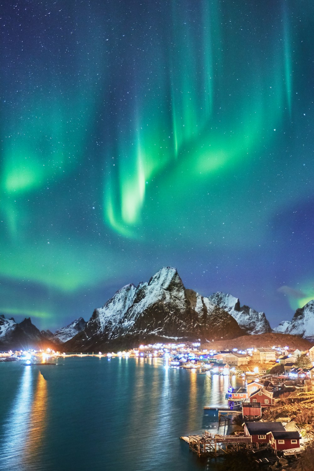 montagnes enneigées près d’un plan d’eau pendant la nuit