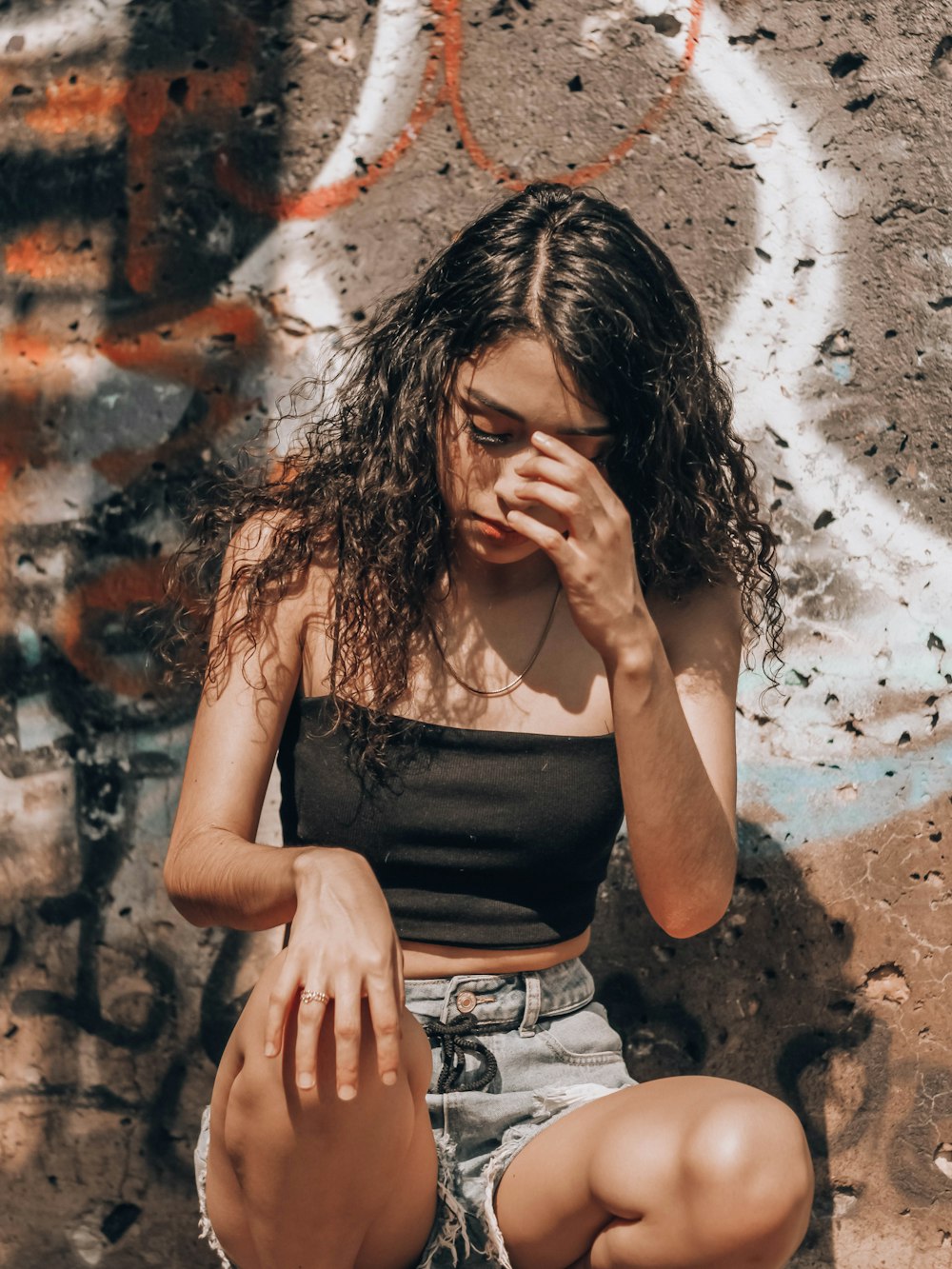 woman in black tank top covering her face with her hands