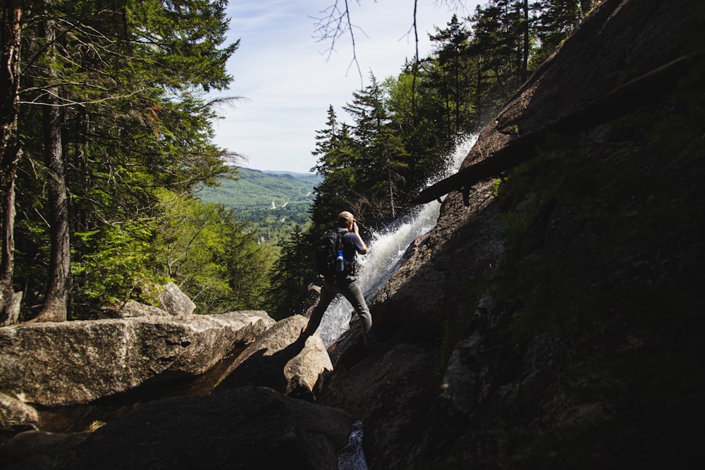 woman in blue jacket and black pants standing on brown rock during daytime