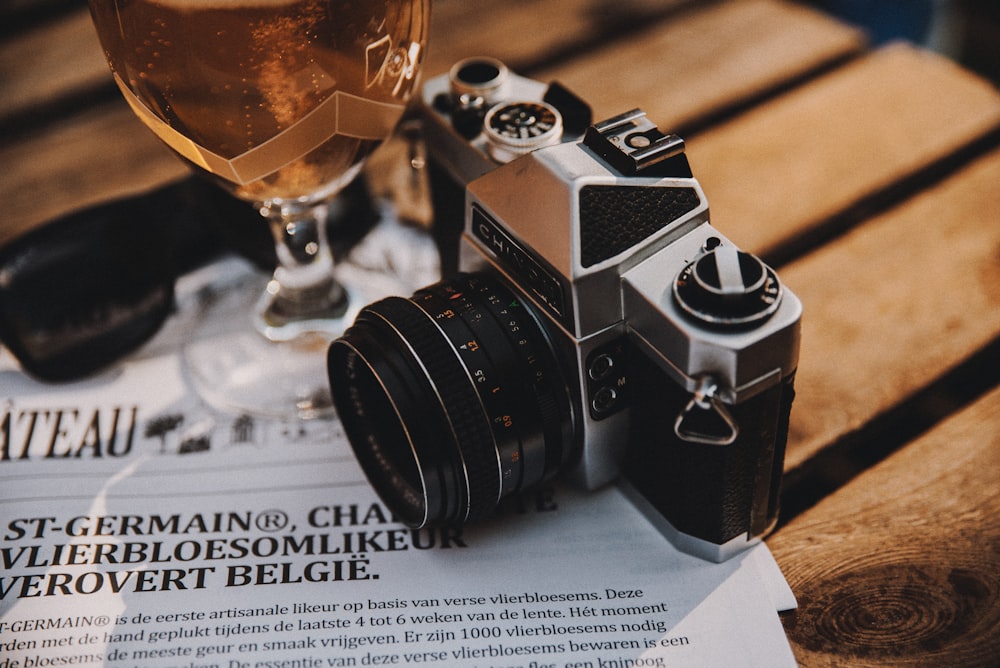 black and silver dslr camera beside clear wine glass