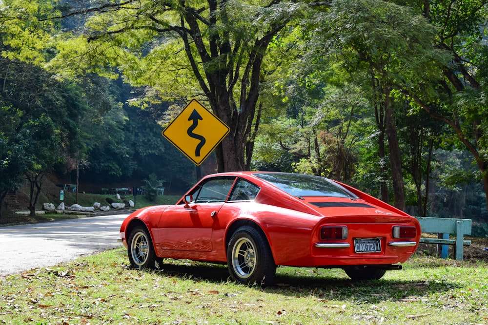 red chevrolet camaro parked on green grass field near body of water during daytime