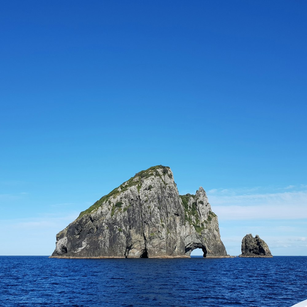 gray rock formation on sea under blue sky during daytime