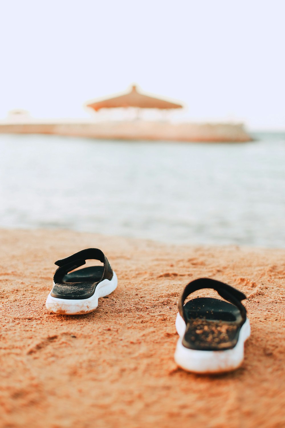 black and white flip flops on brown sand