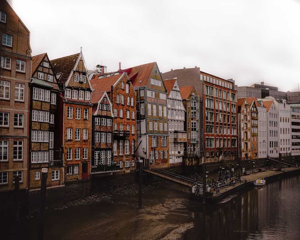 brown and white concrete buildings beside river under white sky during daytime