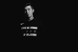 Close-up of a black oversized hoodie with subtle glossy noirvibe logo under moody lighting.