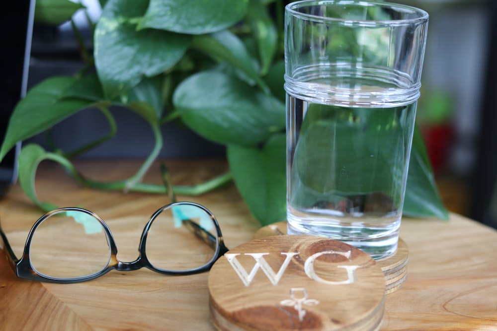 black framed eyeglasses beside clear drinking glass