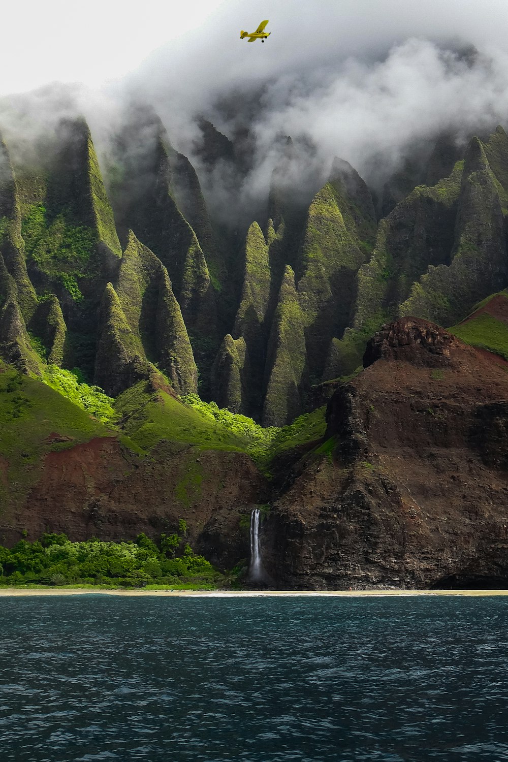 green and brown mountain beside body of water during daytime