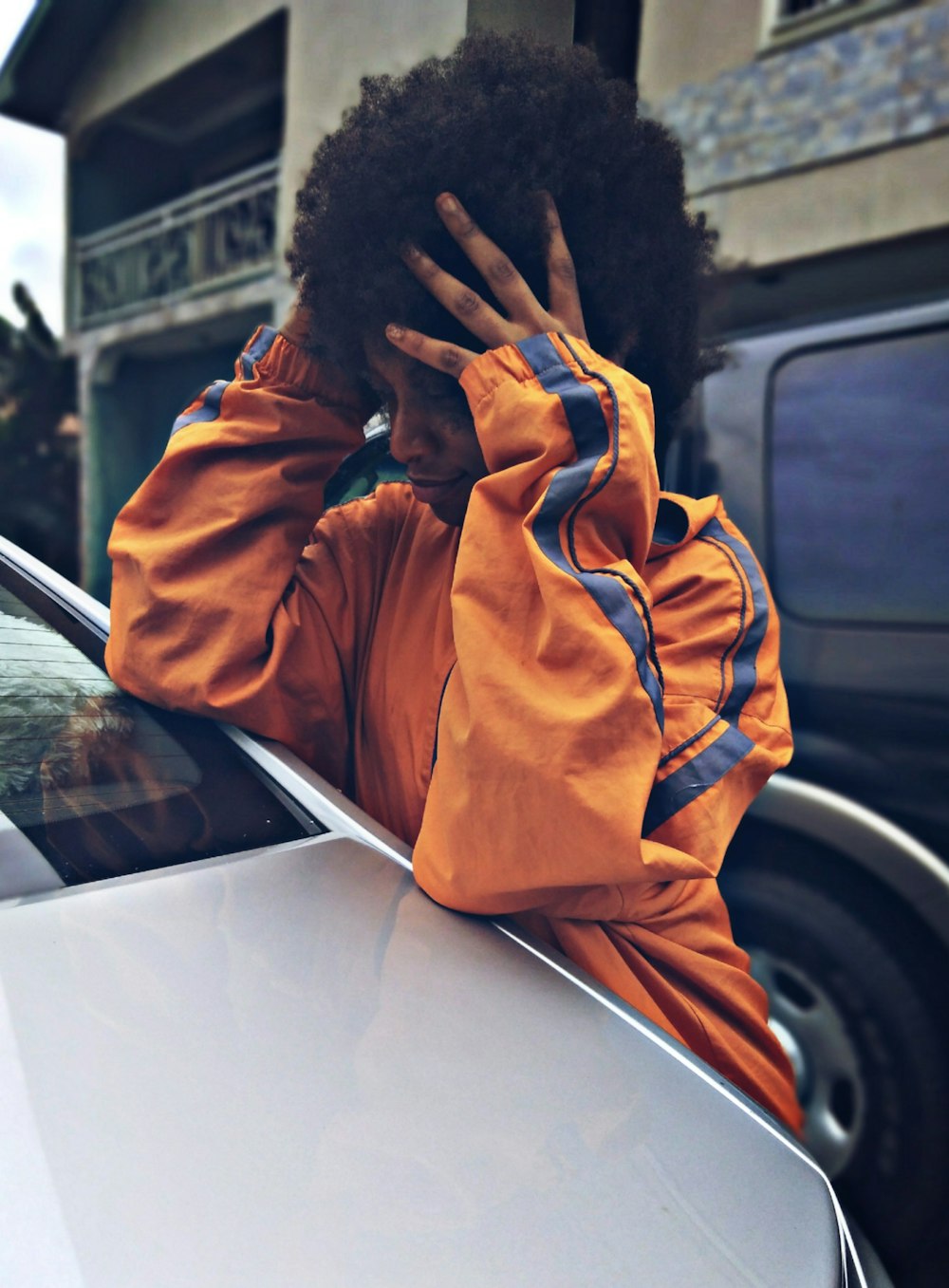 man in orange hoodie covering his face with his hands