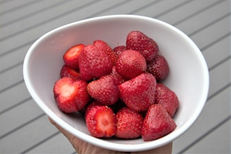 red strawberries in white ceramic bowl