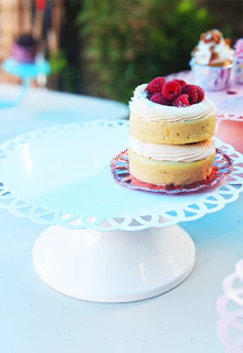 Delicious cakes decorated with fresh fruits and cream on a white cake stand